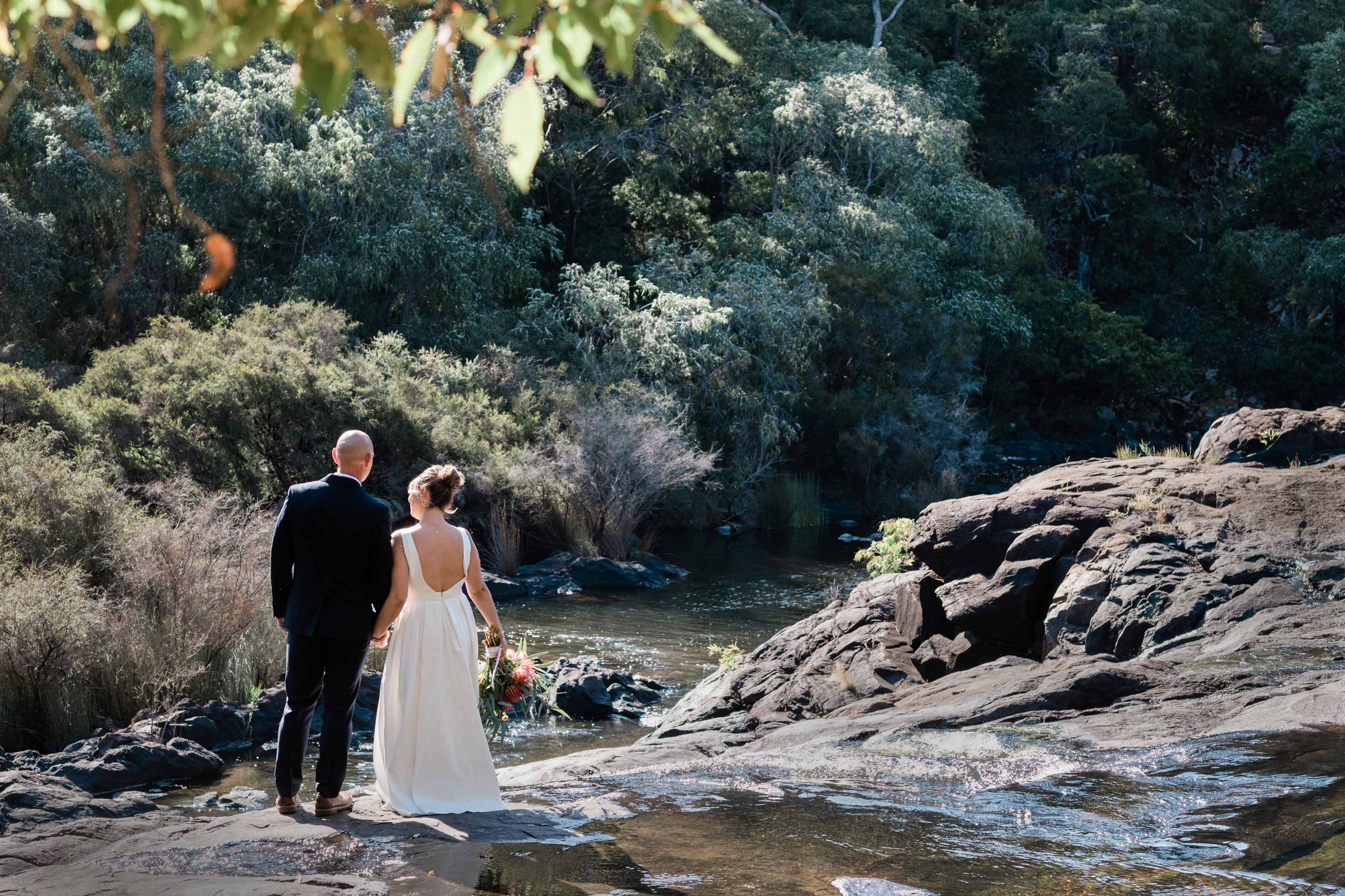 Margaret River waterfall elopement, couple holding hands beside the river surrounded by native bushland, photographed by John Rice
