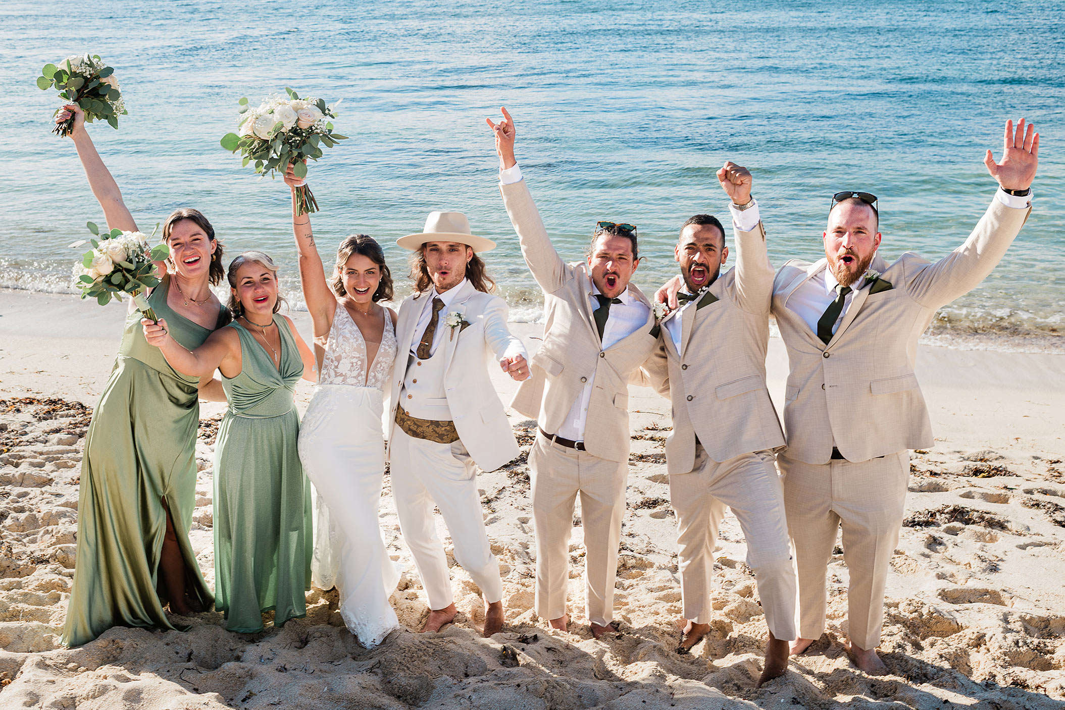 Bride, groom, and wedding party cheering with raised arms on the sand at a Gnarabup Beach wedding in South West WA