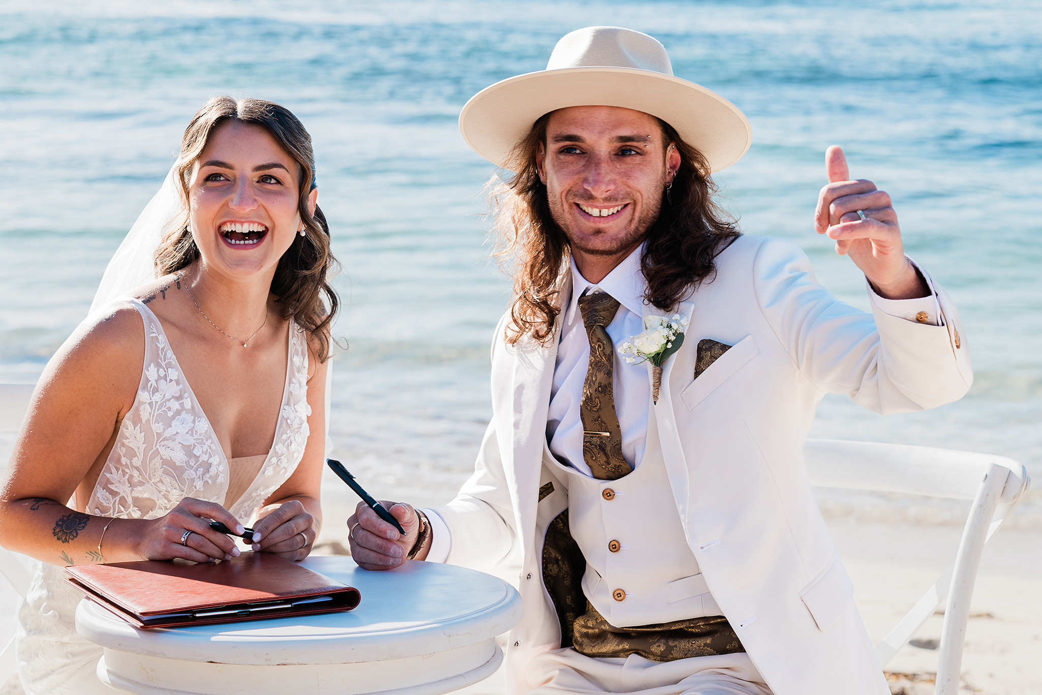 Bride and groom laughing while signing their certificate during an intimate Gnarabup Beach wedding ceremony in Margaret River