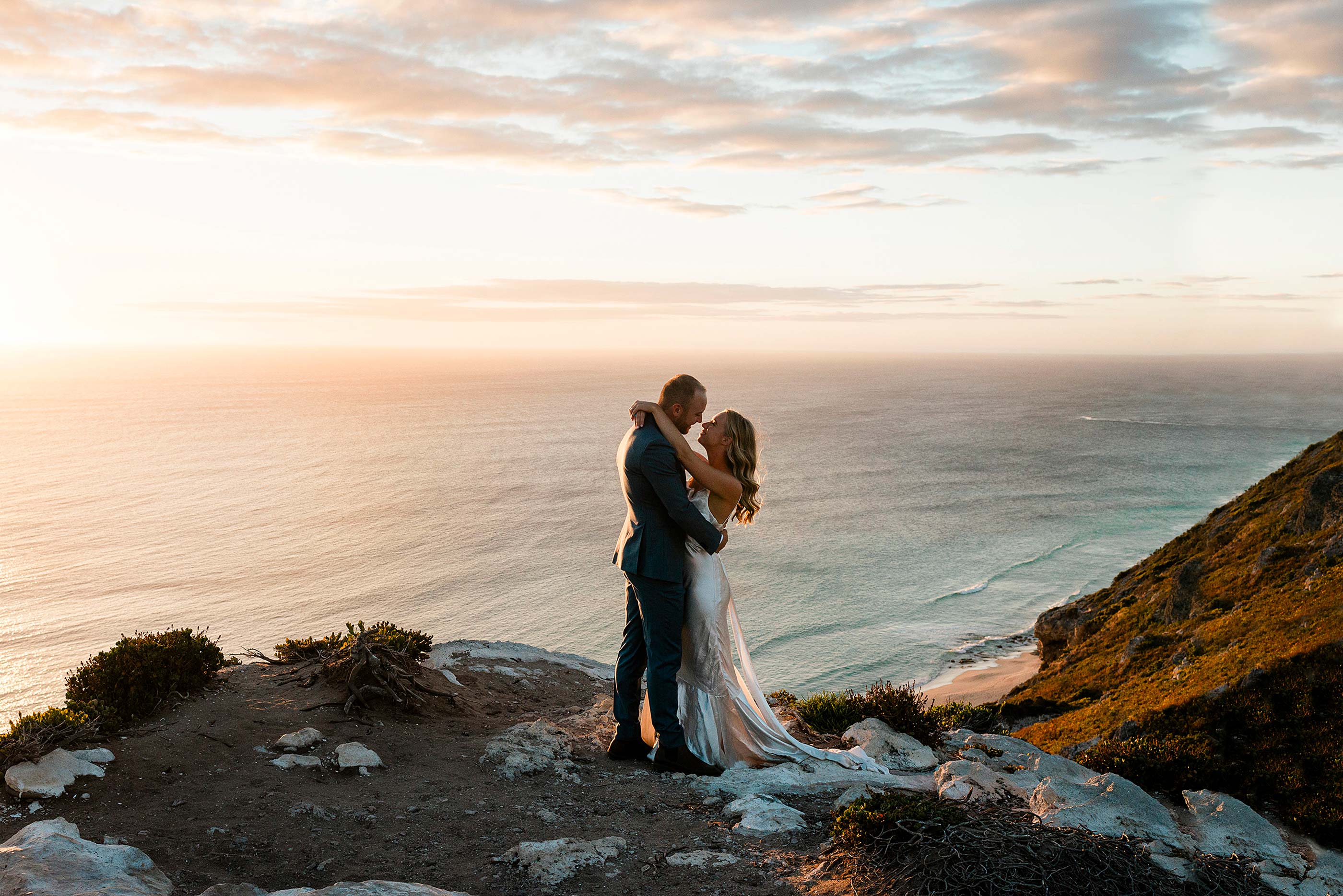 Luxury elopement Margaret River couple kissing at Conto Springs clifftop during golden hour, photographed by John Rice