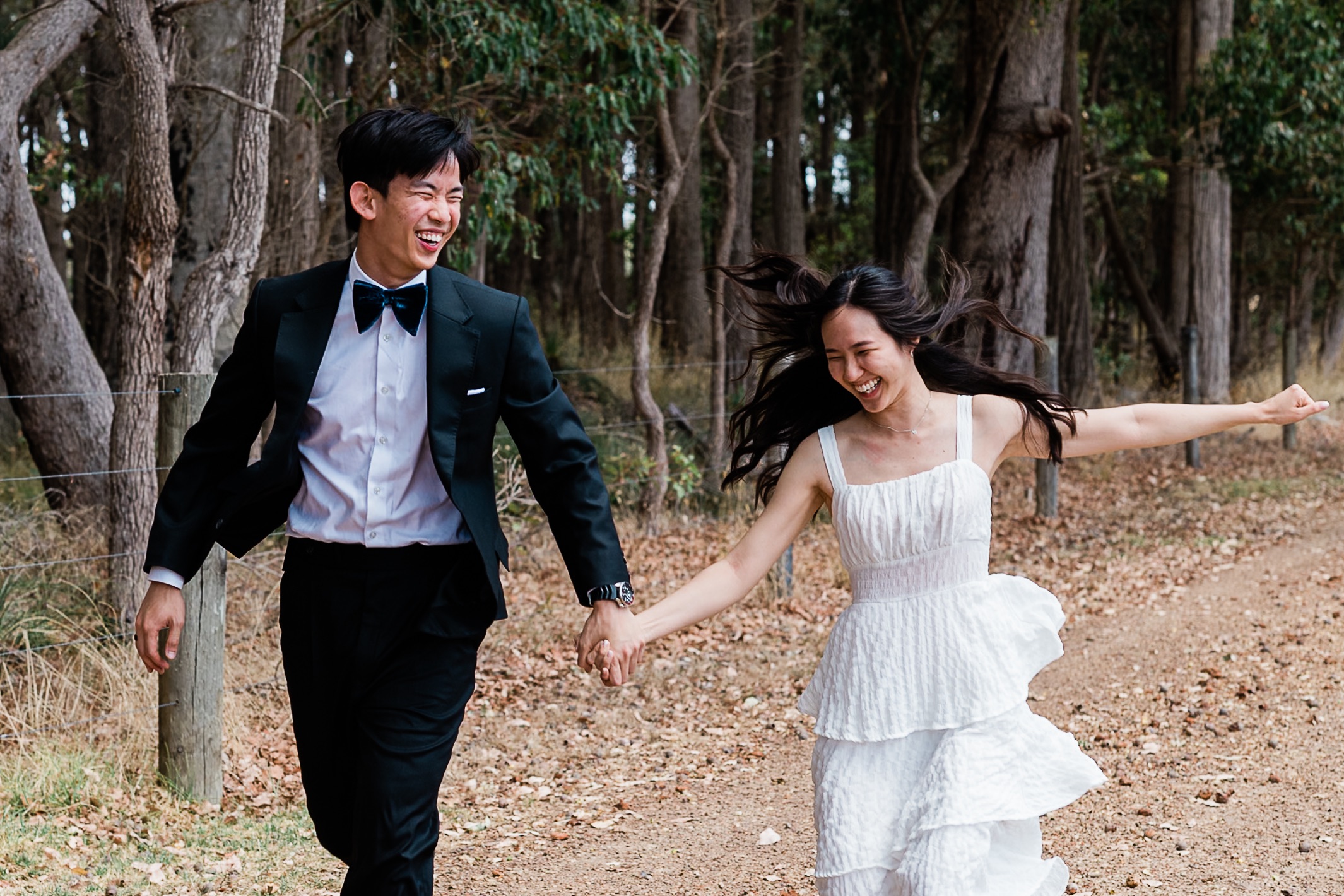 Couple laughing and running through Boranup Forest, Margaret River elopement, photographed by John Rice