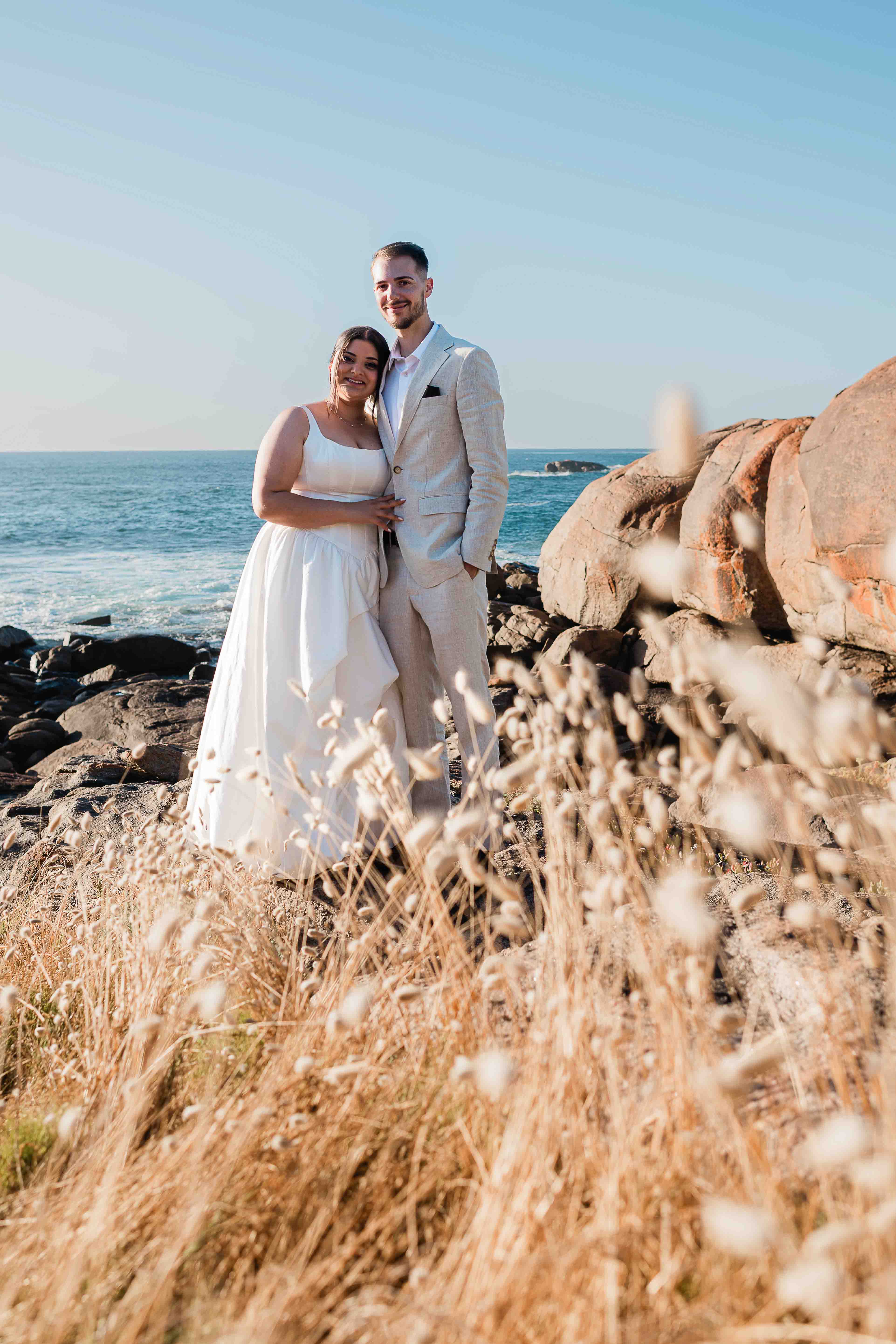 bride groom in beautiful long grass and dramatic rocks golden hour margaret river beach