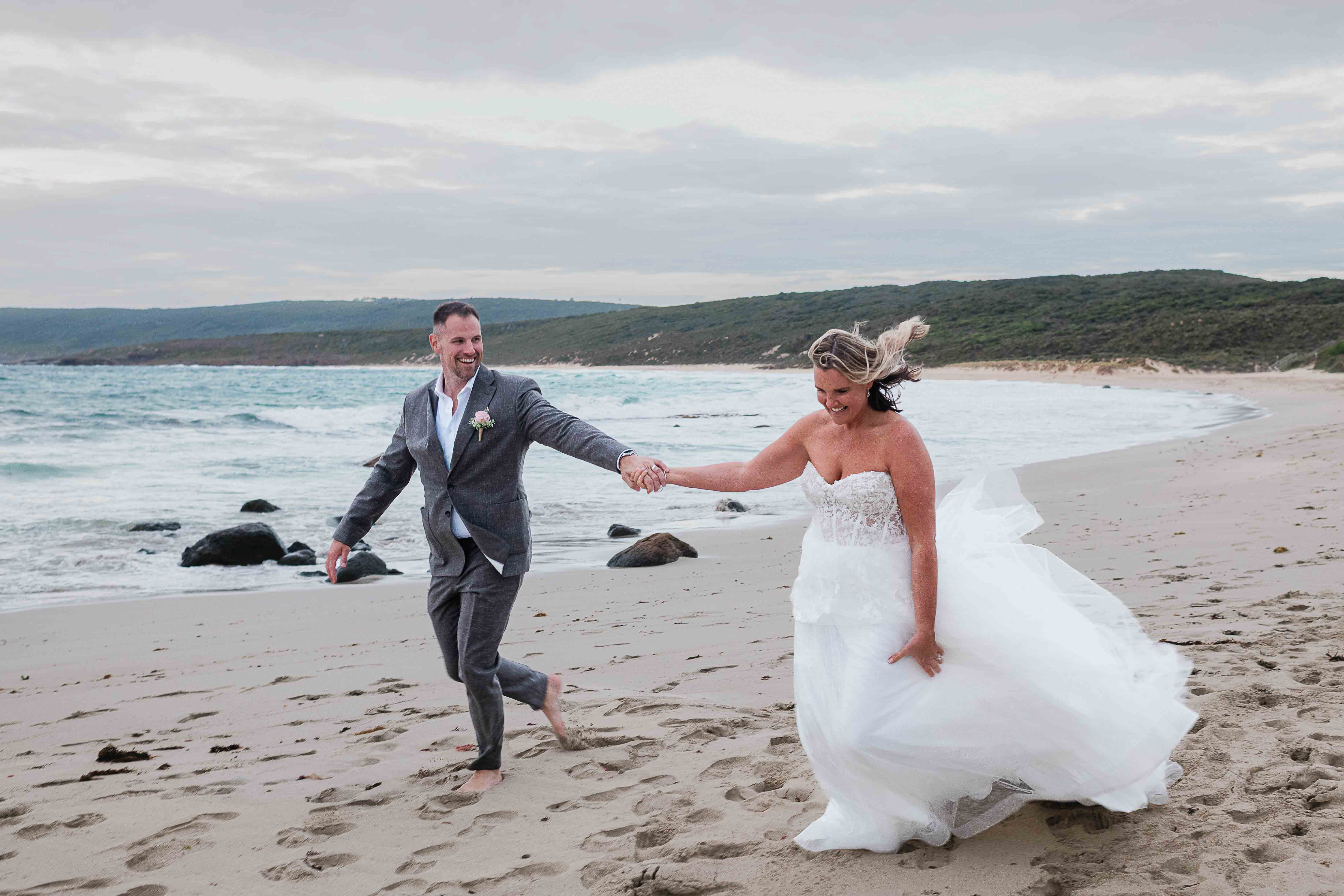 Couple running barefoot on a Margaret River beach after their elopement photography by John Rice.