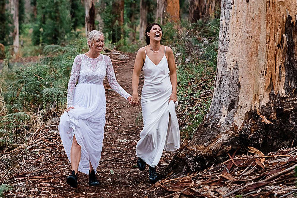 Two brides walking hand in hand through Boranup Forest Margaret River same-sex elopement photography by John Rice.