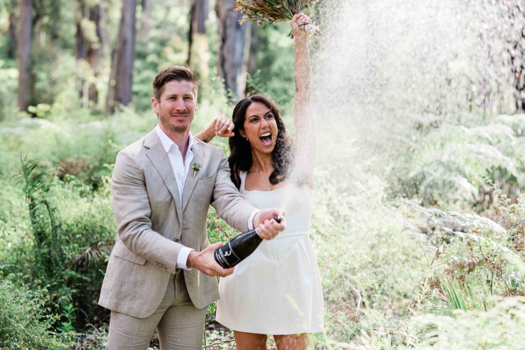 Couple celebrating with champagne at La Foret Enchantee accommodation Margaret River elopement photography by John Rice.
