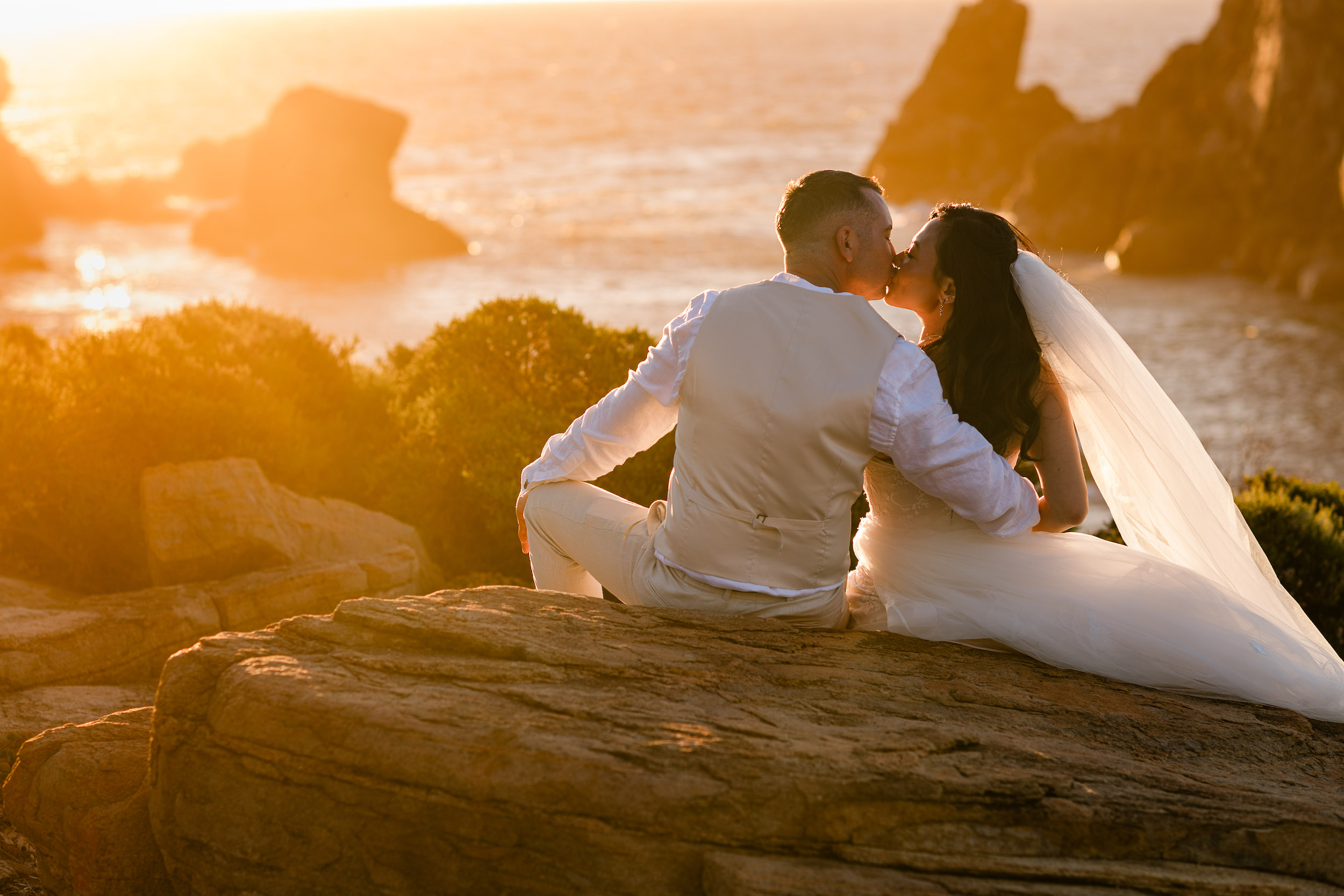 Rachel and Jaren kissing on coastal cliffs at golden hour, Margaret River elopement photography by John Rice