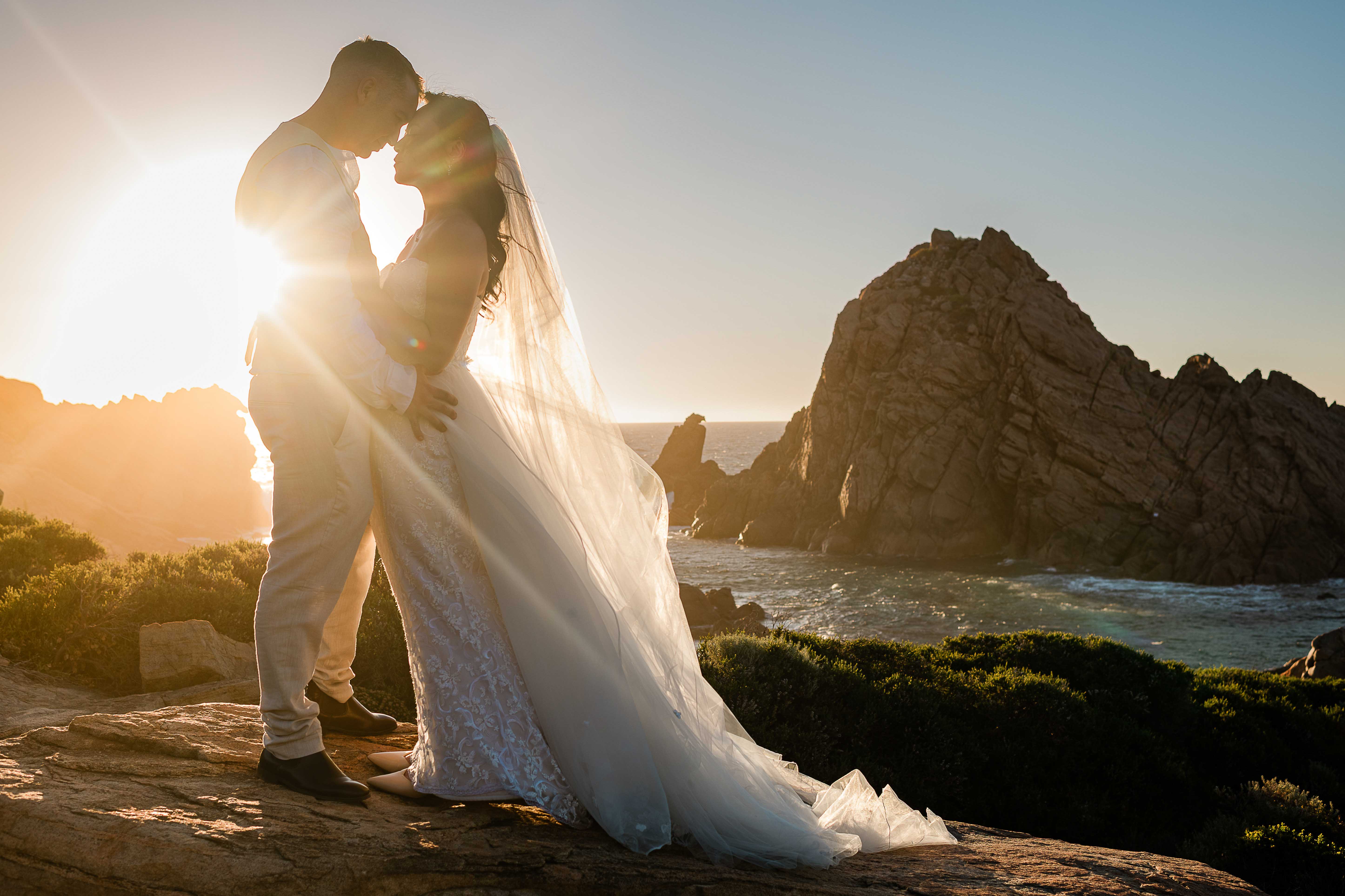 Bride with cathedral veil at Sugarloaf Rock Margaret River at golden hour elopement photography by John Rice.