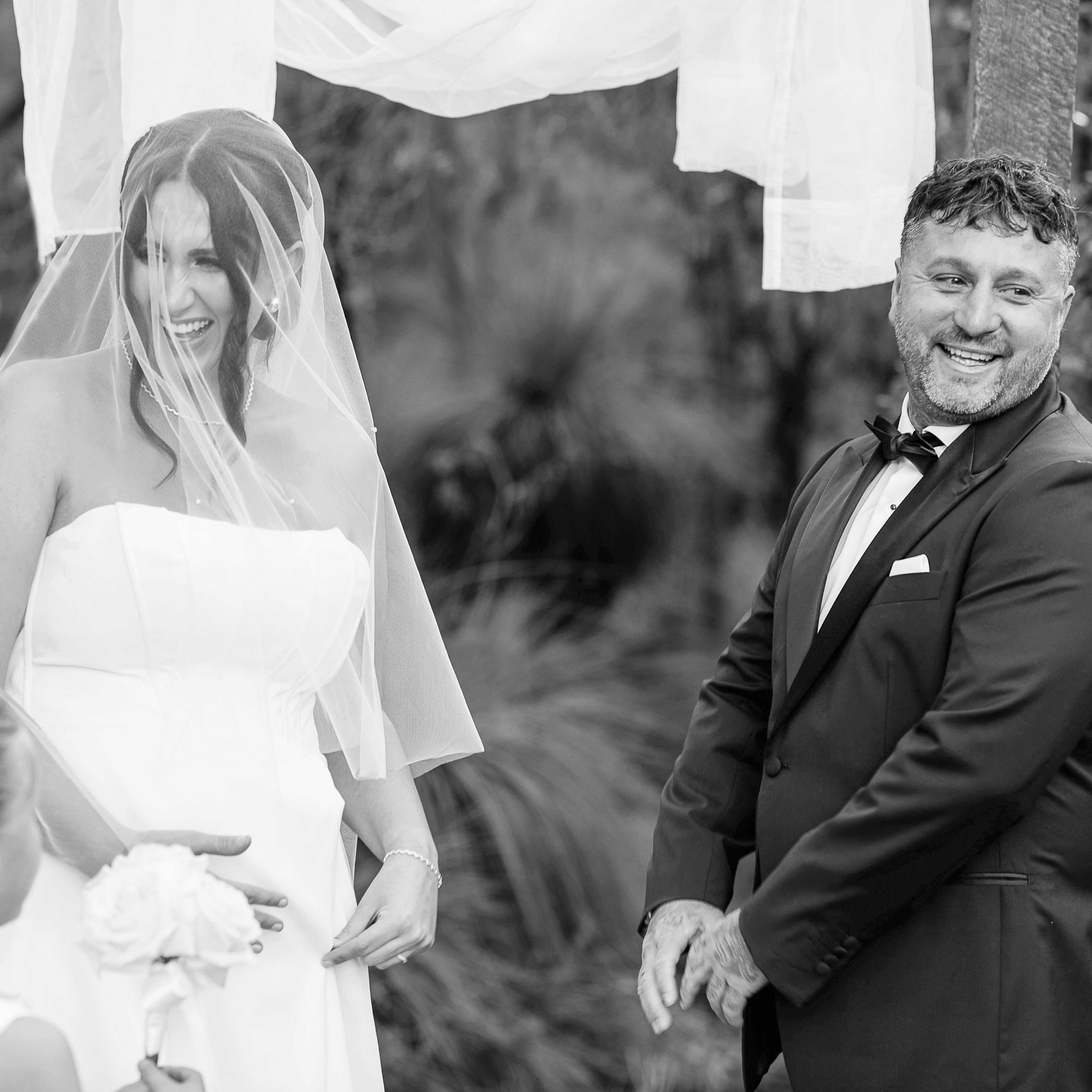 Candid Bina Maya wedding ceremony moment, bride and groom laughing under bushland arch in Yallingup